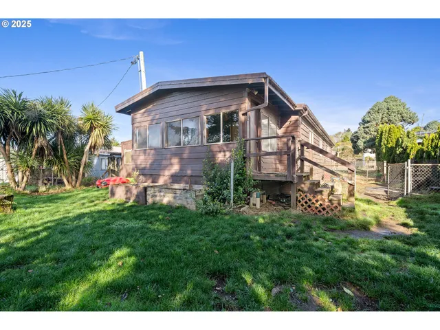 a view of a house with a big yard potted plants and a palm tree
