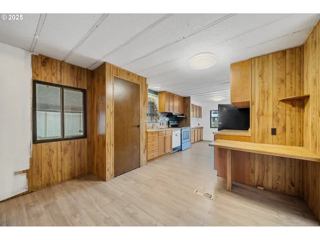 a kitchen with stainless steel appliances kitchen island granite countertop a refrigerator a stove top oven with wooden floor