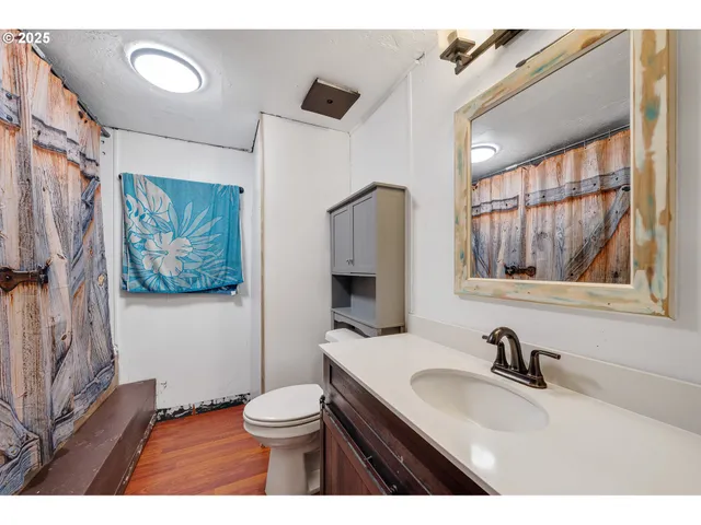 a bathroom with a toilet a sink a mirror a window and vanity