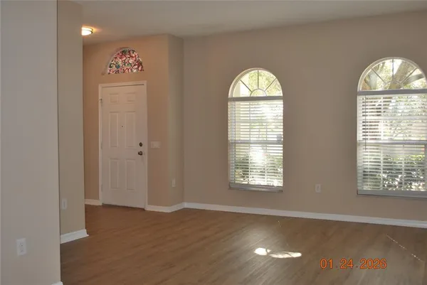 an empty room with wooden floor windows and glass door