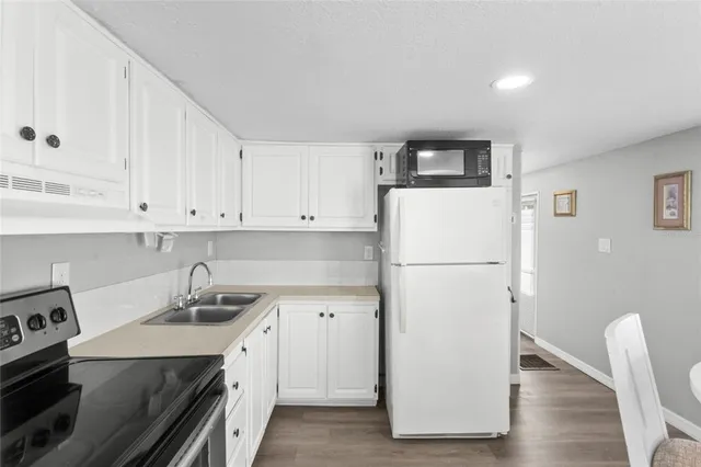 a white refrigerator freezer sitting inside of a kitchen with stainless steel appliances granite countertop a refrigerator sink and cabinets