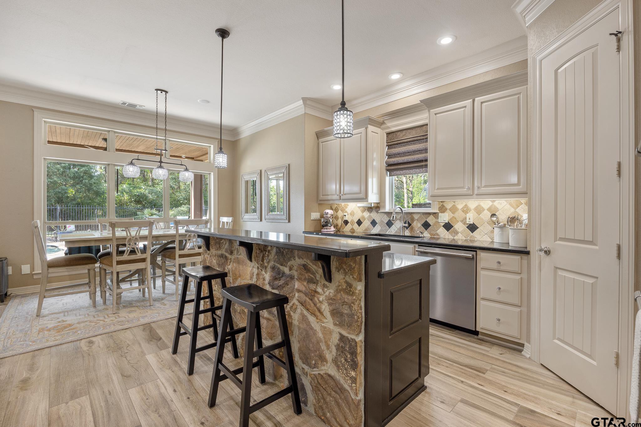 5875 Stonegate Trail Tyler, TX 75703 - Photo 8 of 47 a kitchen with kitchen island granite countertop a table chairs sink and cabinets