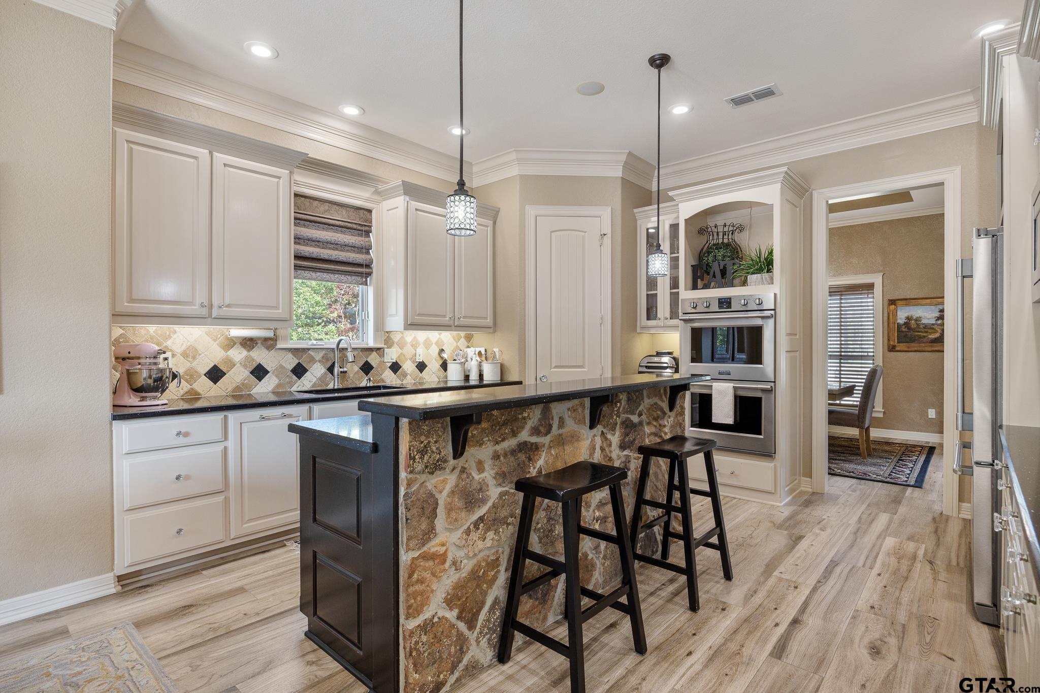 5875 Stonegate Trail Tyler, TX 75703 - Photo 9 of 47 a kitchen with stainless steel appliances kitchen island granite countertop a table chairs sink and cabinets