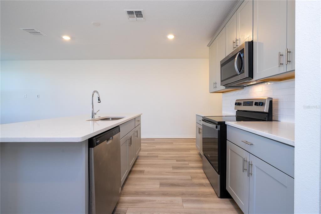 4549 Burrowing Owl Loop St. Cloud, FL 34772 - Photo 15 of 77 a kitchen with stainless steel appliances granite countertop a sink and a stove top oven