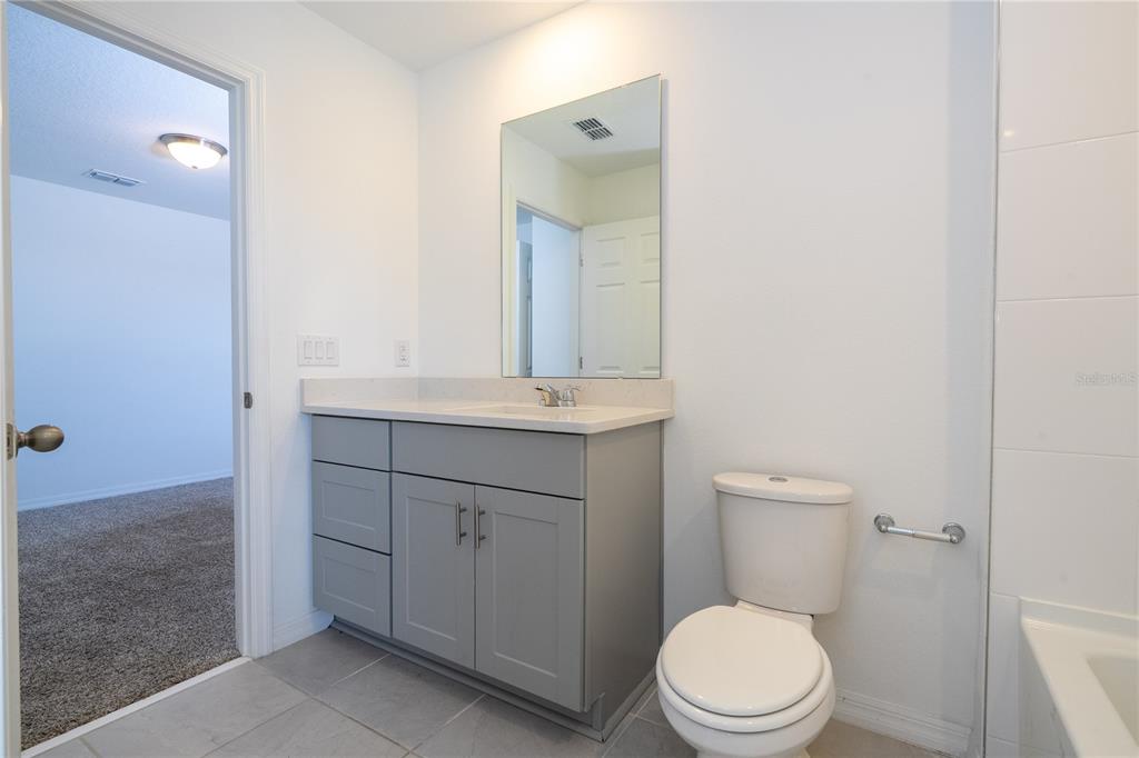 4549 Burrowing Owl Loop St. Cloud, FL 34772 - Photo 38 of 77 a bathroom with a toilet a sink a vanity and mirror