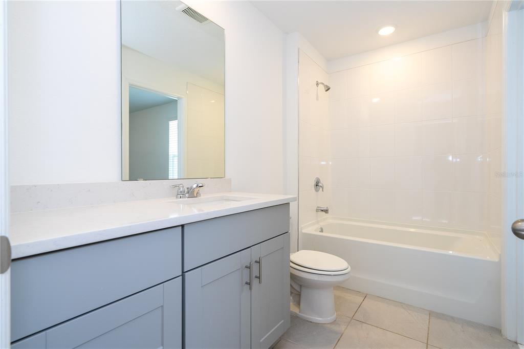 4549 Burrowing Owl Loop St. Cloud, FL 34772 - Photo 43 of 77 a bathroom with a granite countertop sink toilet a large mirror a bathtub and shower