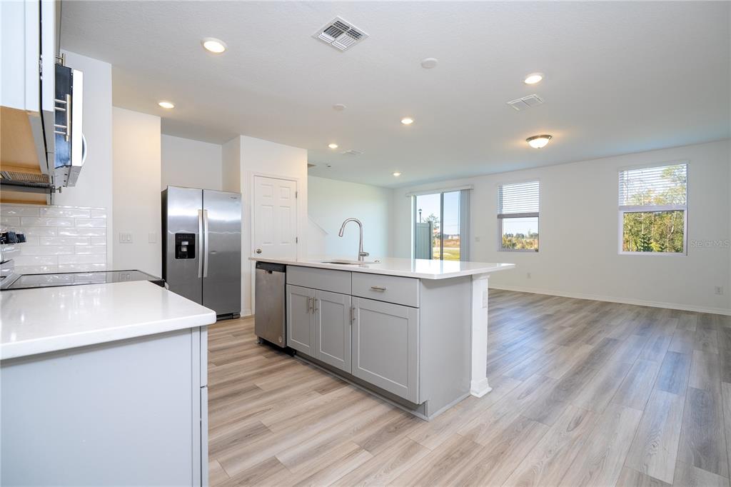 4549 Burrowing Owl Loop St. Cloud, FL 34772 - Photo 5 of 77 a kitchen with stainless steel appliances granite countertop a refrigerator a sink dishwasher and a oven with wooden floors