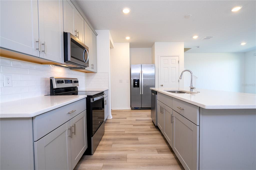 4549 Burrowing Owl Loop St. Cloud, FL 34772 - Photo 6 of 77 a kitchen with stainless steel appliances granite countertop a refrigerator a stove top oven a sink and dishwasher