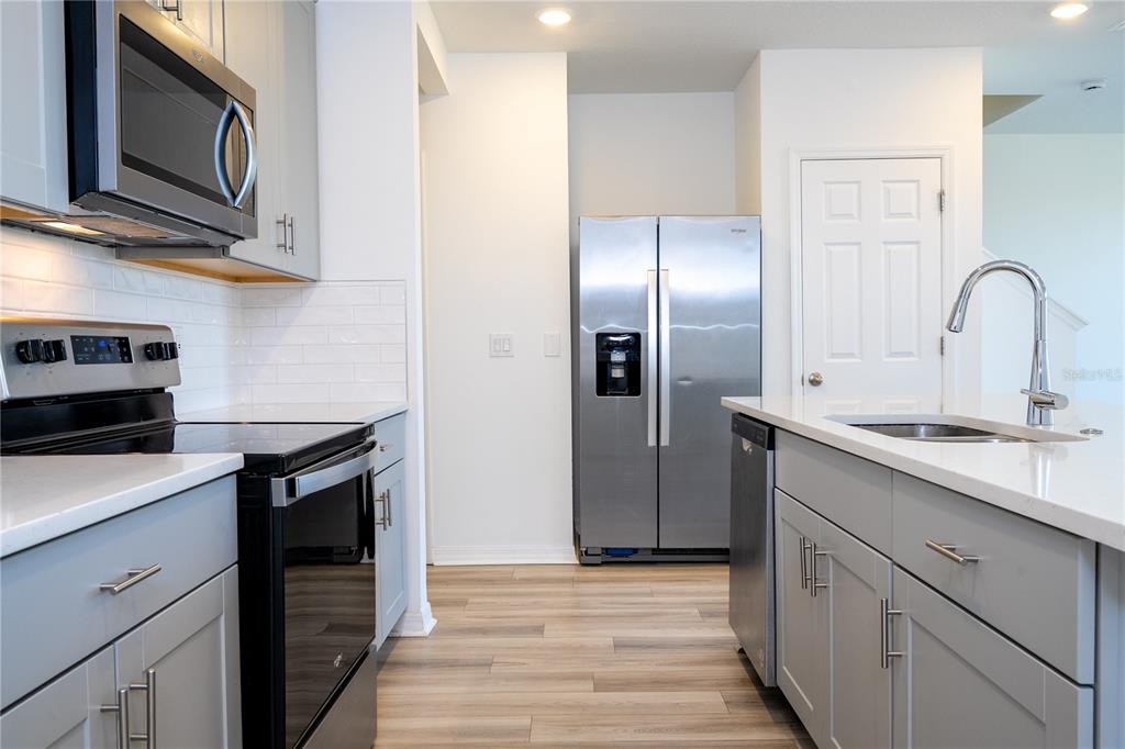 4549 Burrowing Owl Loop St. Cloud, FL 34772 - Photo 7 of 77 a kitchen with stainless steel appliances granite countertop a refrigerator a stove and a sink with wooden floor