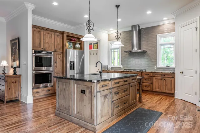 a kitchen with stainless steel appliances granite countertop a sink a stove and a wooden floors