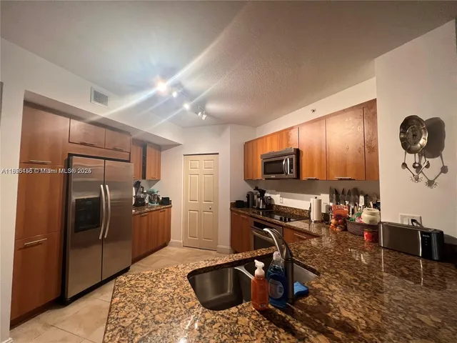 a kitchen with stainless steel appliances granite countertop a refrigerator and a sink