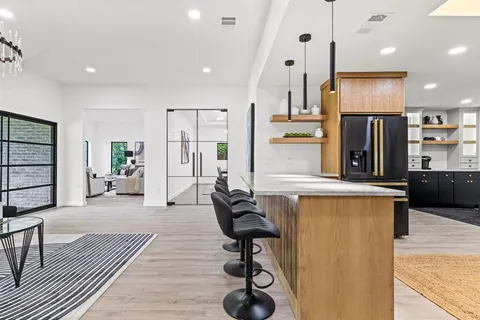 a kitchen with stainless steel appliances kitchen island granite countertop a refrigerator and a stove top oven with wooden floor