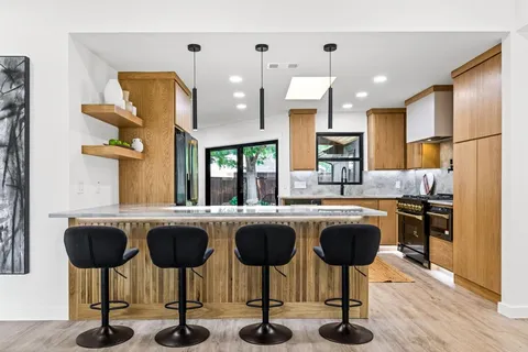 a kitchen with stainless steel appliances granite countertop a table chairs stove and refrigerator