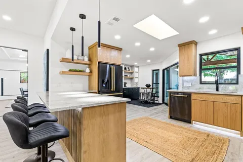 a living room with stainless steel appliances kitchen island granite countertop furniture and a large window