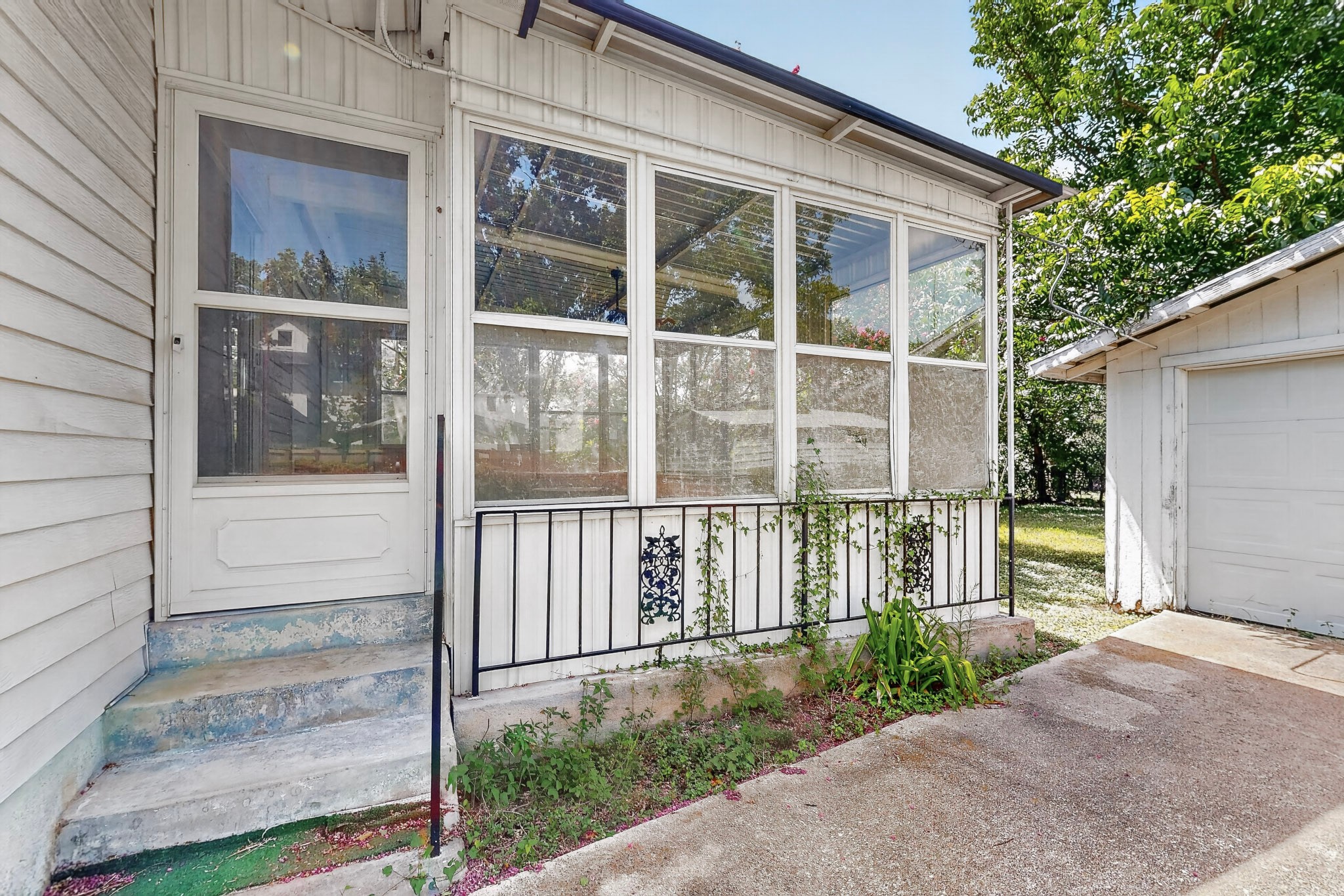 4703 Leslie Avenue Austin, TX 78721 - Photo 28 of 34 Step up to a charming entry featuring a white screened door and an inviting sun porch with a decorative railing.