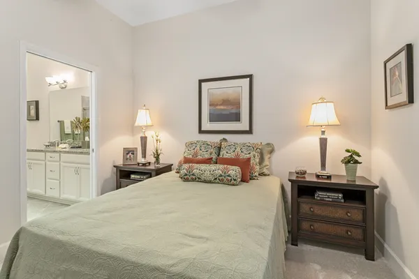a bedroom with a bed and a lamp on dresser