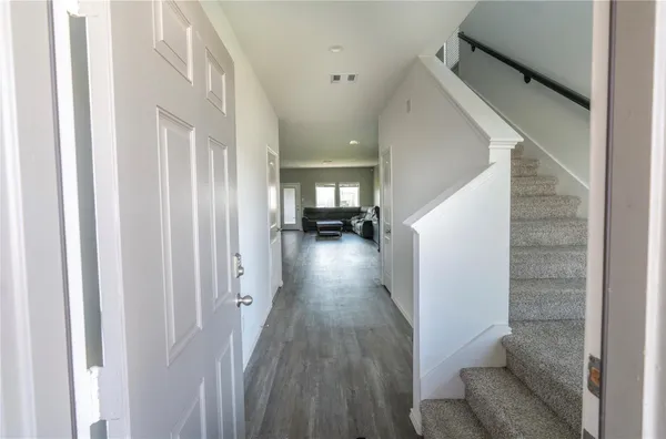 a view of a hallway with wooden floor and stairs