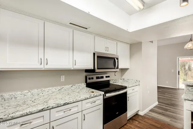 a kitchen with granite countertop white cabinets and a stove