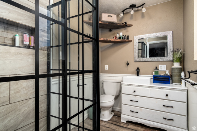 100 Third North Helper, UT 84526 - Photo 22 of 30 Bathroom featuring a black-grid glass shower enclosure, a tiled shower interior with a recessed niche, a white vanity with drawer storage, a mounted mirror, and wood-finish flooring