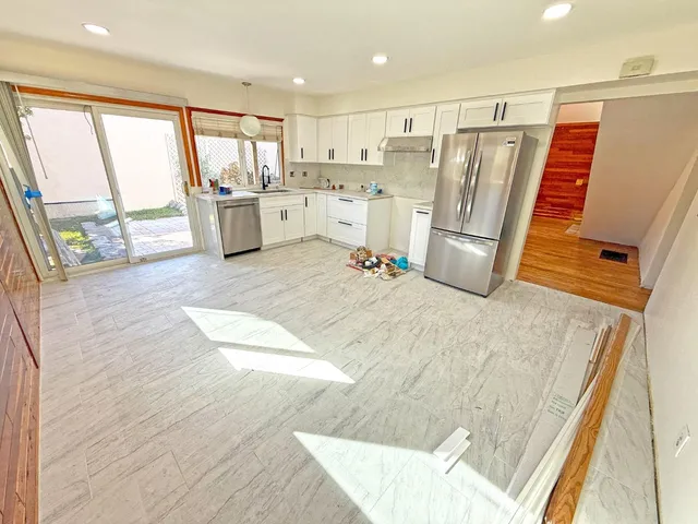 a large white kitchen with wooden floors and stainless steel appliances