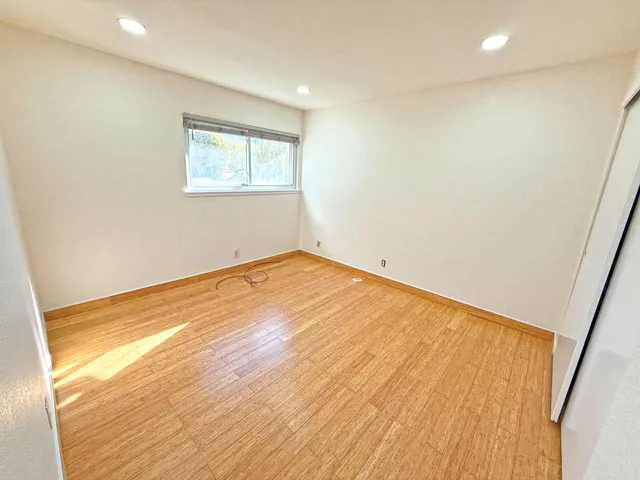 a view of empty room with wooden floor and fan