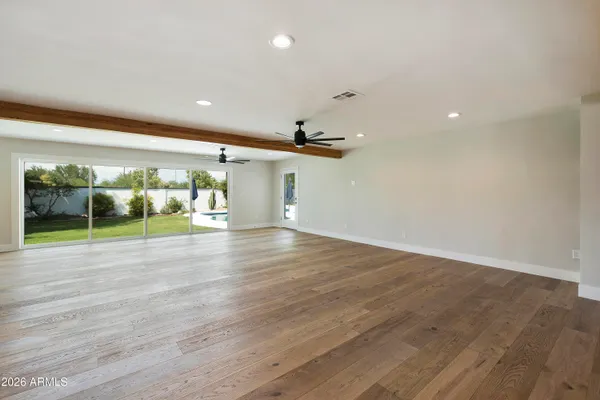 a view of an empty room with wooden floor and a kitchen