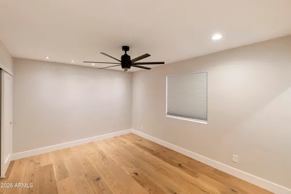 a view of empty room with wooden floor and fan