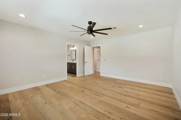 an empty room with wooden floor ceiling fan and windows