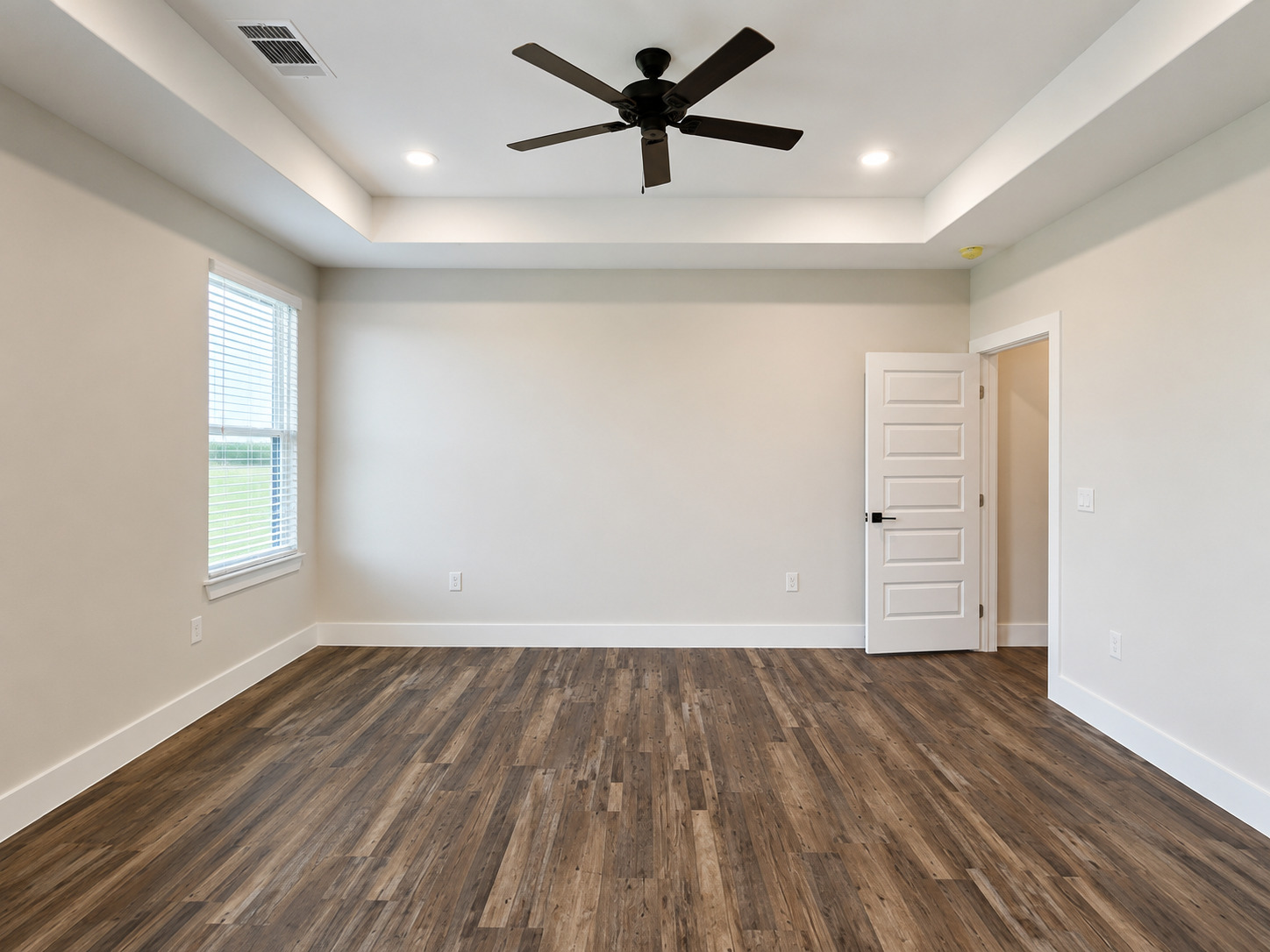 488 County Road 468 Elgin, TX 78621 - Photo 8 of 12 A spacious bedroom features rich wood flooring, a modern ceiling fan, and recessed lighting in a tray ceiling.