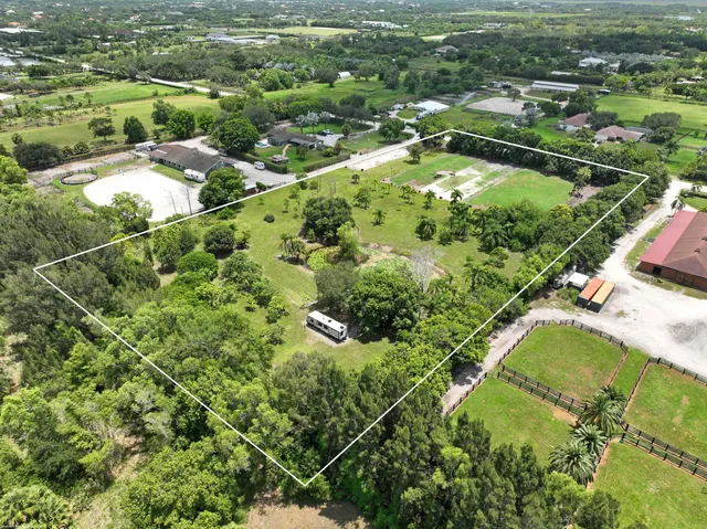 an aerial view of residential houses with outdoor space and trees