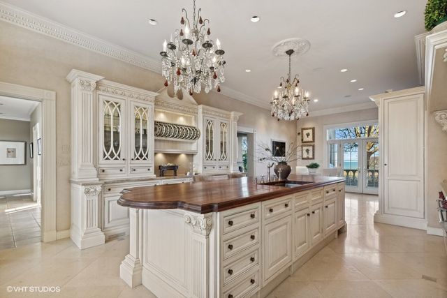 a view of a kitchen island a chandelier and cabinets