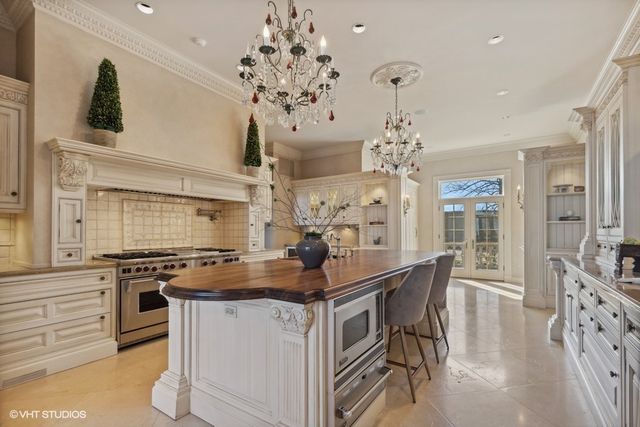 a kitchen with stainless steel appliances a stove a chandelier and a dining table