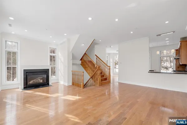 an empty room with wooden floor fireplace and windows