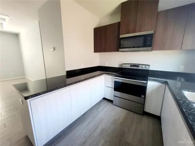 a kitchen with granite countertop white cabinets and stainless steel appliances
