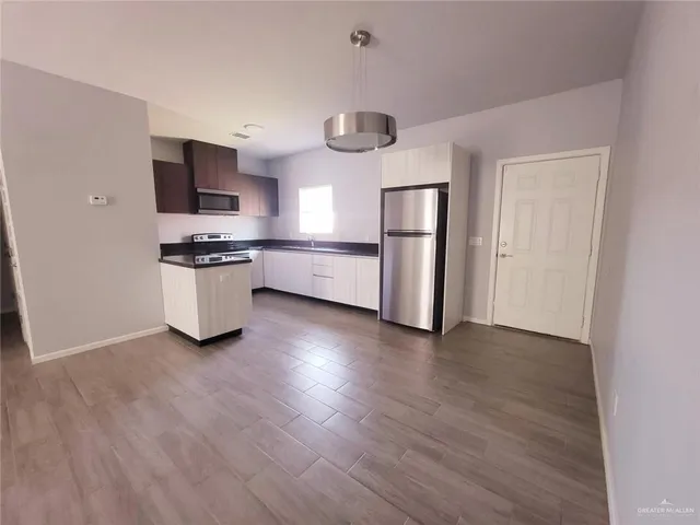 a kitchen with stainless steel appliances granite countertop a refrigerator a stove top oven a sink dishwasher and wooden floor