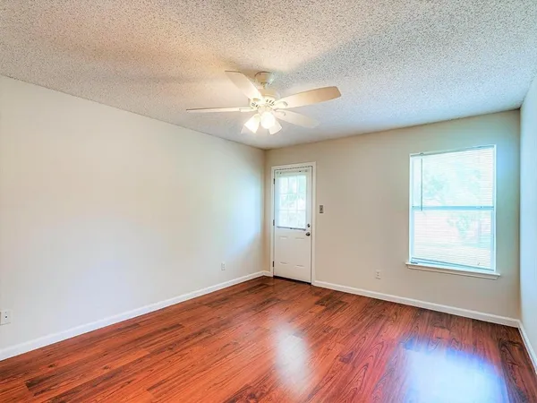 an empty room with wooden floor and windows