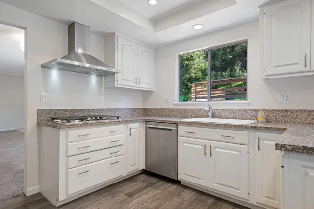 a kitchen with granite countertop white cabinets and window