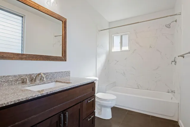 a bathroom with a granite countertop sink toilet and shower