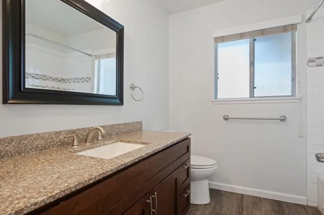 a bathroom with a granite countertop toilet sink and mirror