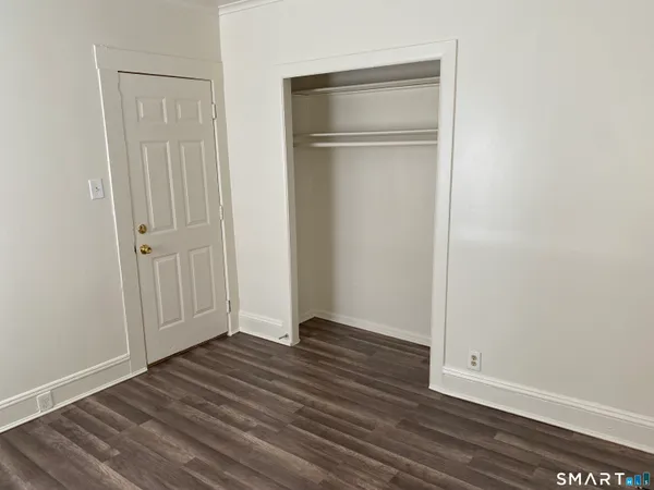 an empty room with wooden floor & closet area