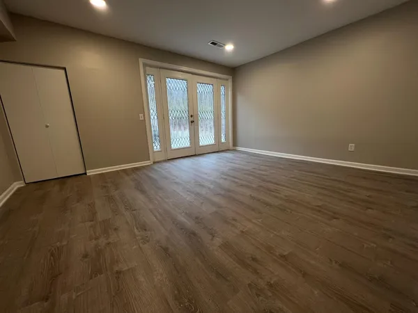 an empty room with wooden floor and windows