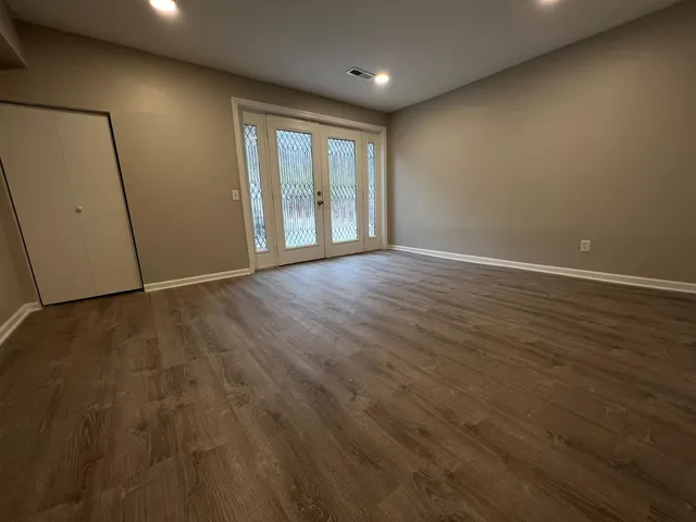 an empty room with wooden floor and windows