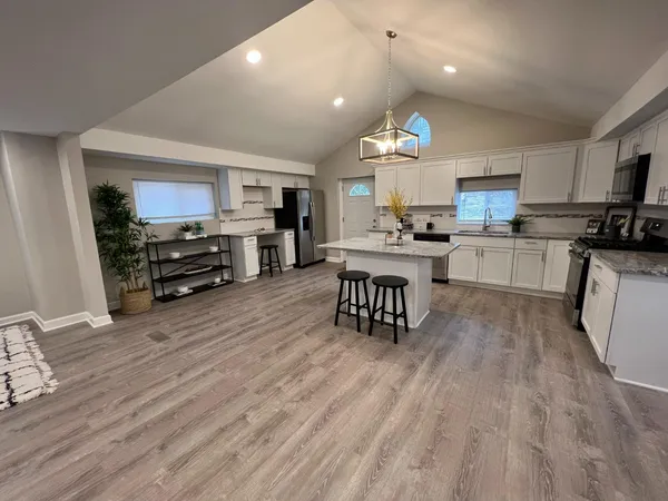 a kitchen with a refrigerator a stove top oven a sink dishwasher and white cabinets with wooden floor