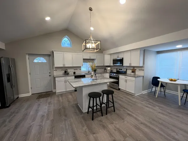 a open kitchen with white cabinets stainless steel appliances and dining table