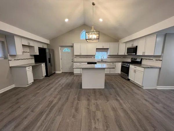 a kitchen with stainless steel appliances a sink stove and wooden floor