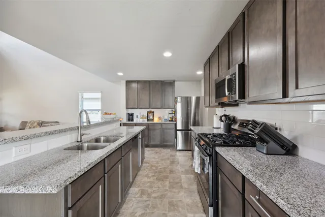 a kitchen with stainless steel appliances granite countertop a sink a stove and a refrigerator