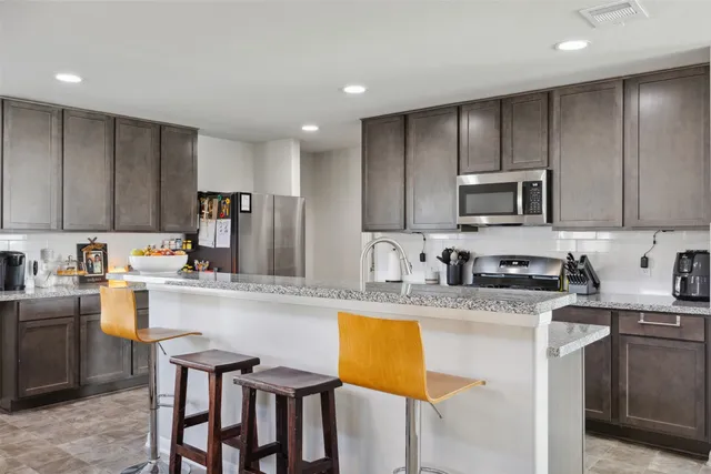 a kitchen with stainless steel appliances granite countertop a stove top oven a sink refrigerator and cabinets