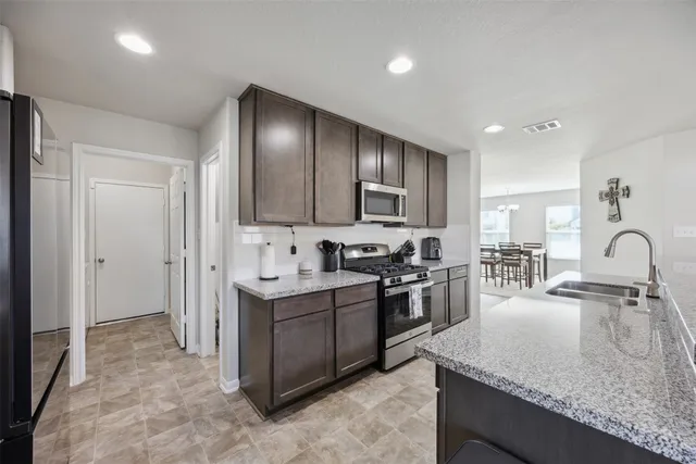 a kitchen with stainless steel appliances granite countertop a sink stove and refrigerator