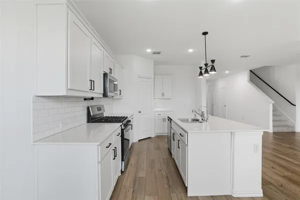 a kitchen with stainless steel appliances granite countertop a sink a stove and a refrigerator