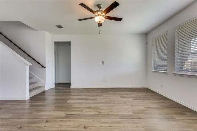 a view of an empty room with window and wooden floor